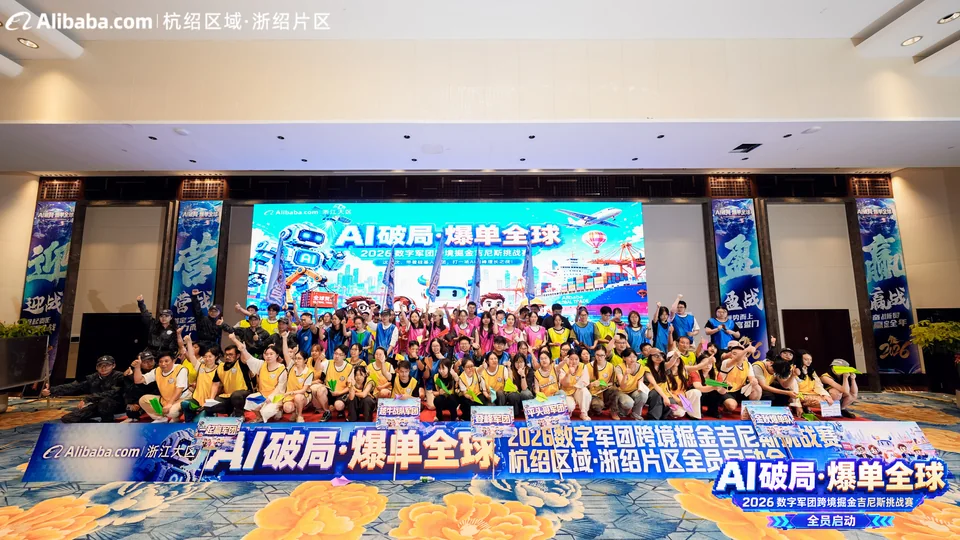 Une large photo de groupe des participants, réunis en rangées dans la salle devant la scène.