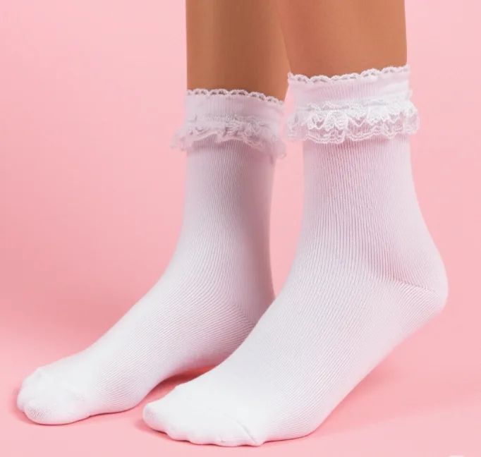 Weiße Söckchen mit gerüschten Spitzenbündchen vor rosa Hintergrund Weiße Söckchen mit gerüschten Spitzenbündchen vor rosa Hintergrund