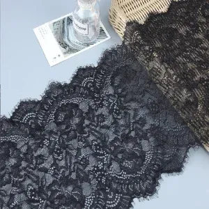 Breite schwarze Blumenspitze mit Bogenkanten, diagonal auf einer grauen Fläche ausgelegt.
