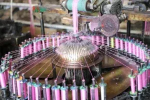 Employee threading yarn into industrial lace-making equipment. Employee threading yarn into industrial lace-making equipment.