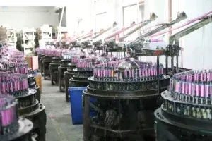 Factory floor showing a worker and weaving machinery surrounded by lace materials. Factory floor showing a worker and weaving machinery surrounded by lace materials.