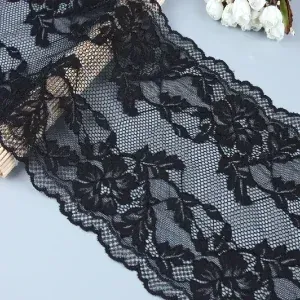 Black floral lace with scalloped edges on a gray surface beside white flowers. Black floral lace with scalloped edges on a gray surface beside white flowers.