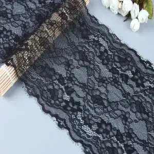 Detailed black floral lace trim ideal for dressmaking, sewing projects, and decorative crafts, showcasing delicate and soft fabric texture. Detailed black floral lace trim ideal for dressmaking, sewing projects, and decorative crafts, showcasing delicate and soft fabric texture.