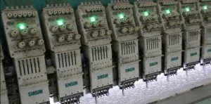 Imagen panorámica de una gran fábrica de encaje con varias líneas de bordado trabajando simultáneamente para producir encajes finos.
