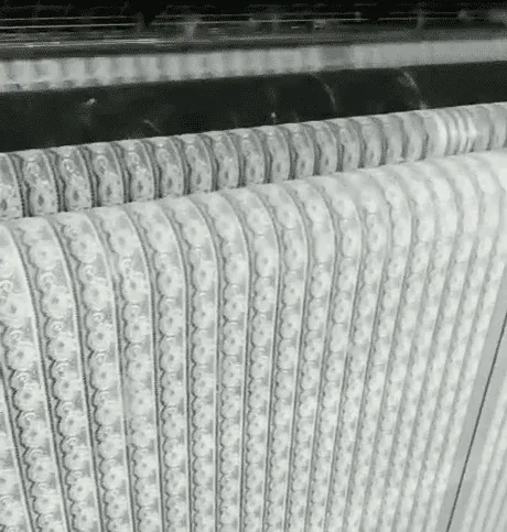 Weiße Spitze mit wiederholten schmalen Blumenbändern über Rollen gespannt. Weiße Spitze mit wiederholten schmalen Blumenbändern über Rollen gespannt.