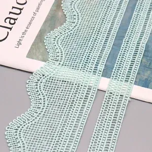Mintgrüne Spitzenborte mit Gittermuster und Bogenkante auf bedrucktem Papier. Mintgrüne Spitzenborte mit Gittermuster und Bogenkante auf bedrucktem Papier.