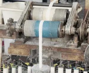 Gros plan de rouleaux couverts de fil et de fils blancs traversant une machine textile. Gros plan de rouleaux couverts de fil et de fils blancs traversant une machine textile.