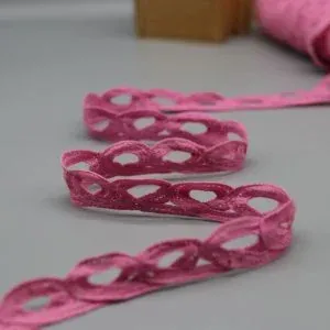 Pink trim with repeating oval openings arranged in loops on a gray surface.