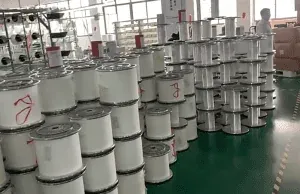 Large white thread spools stacked in groups on a green workshop floor.
