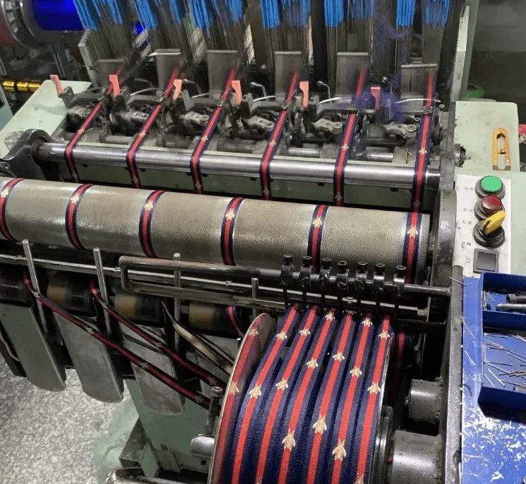 Close-up of quality-control stations and computerized machines for inserting piping cords and weaving grosgrain, showing trial runs and tests to obtain soft, durable trims for garment Original Equipment Manufacturers (OEM). Close-up of quality-control stations and computerized machines for inserting piping cords and weaving grosgrain, showing trial runs and tests to obtain soft, durable trims for garment Original Equipment Manufacturers (OEM).