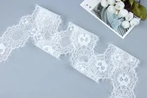 Nebeneinander angeordnete Nahaufnahmen weißer Häkelspitze mit Perlen und zarter weißer Stickspitzenborte, ideal für Brautkleider und Accessoires.