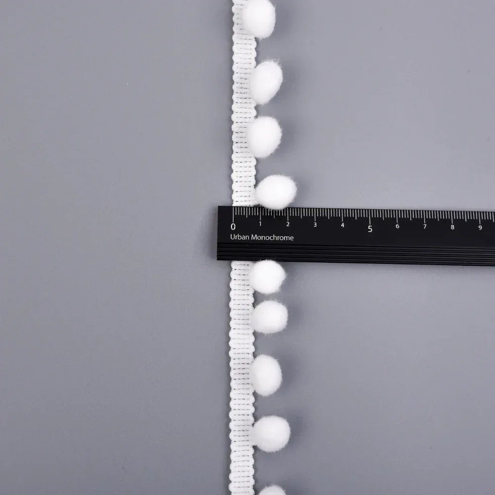 Détail de la bande crochetée festonnée et des points de fixation des pompons