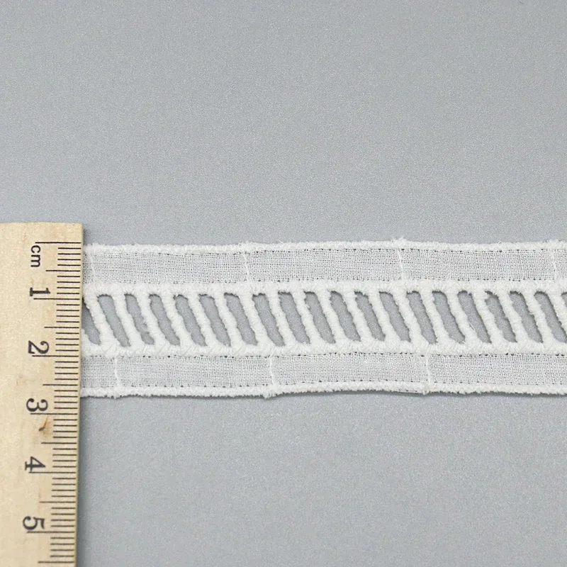Vue en biais montrant la texture mate du coton et l’épaisseur des points de broderie en relief Vue en biais montrant la texture mate du coton et l’épaisseur des points de broderie en relief