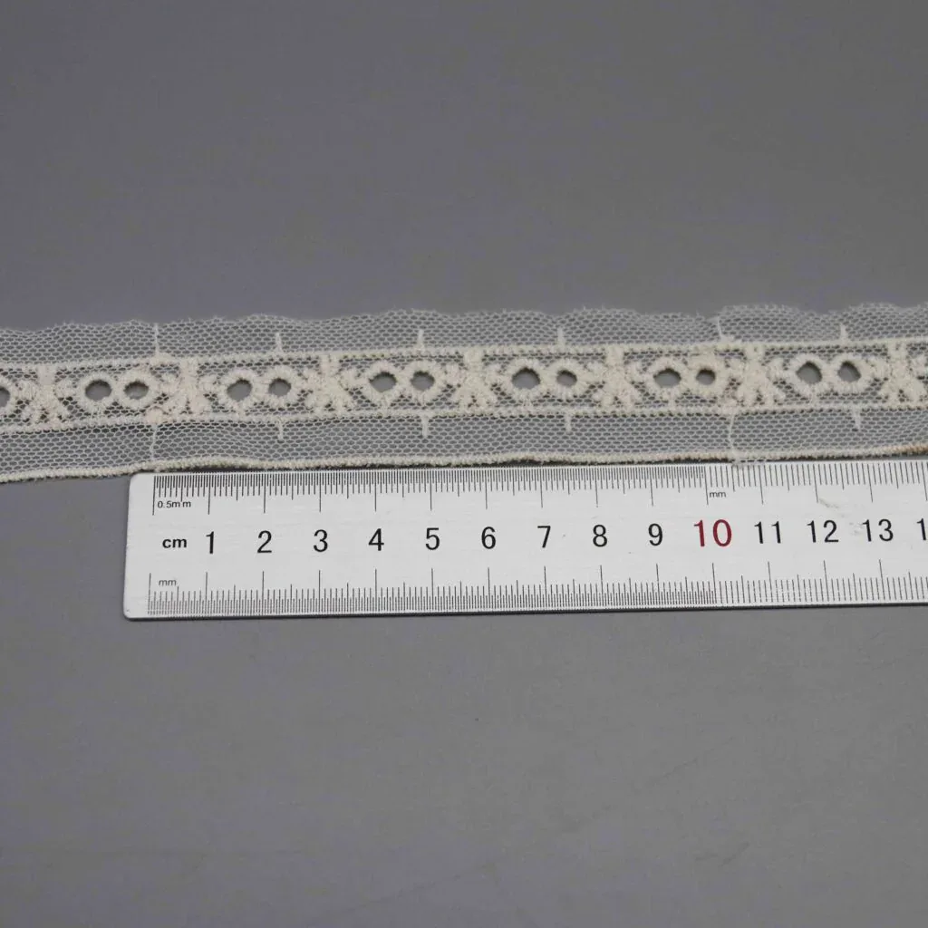 Règle placée horizontalement le long des œillets et papillons pour montrer l’échelle et l’espacement des motifs