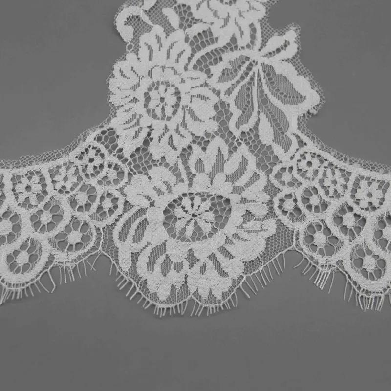 Close-up of a large flower and rows of open loops along the fringed lower edge of white lace.