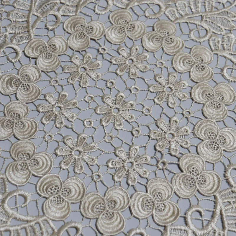 Nahansicht der offenen Verbindungen zwischen kleinen Blumen in der Mitte einer beigen Spitzendecke.