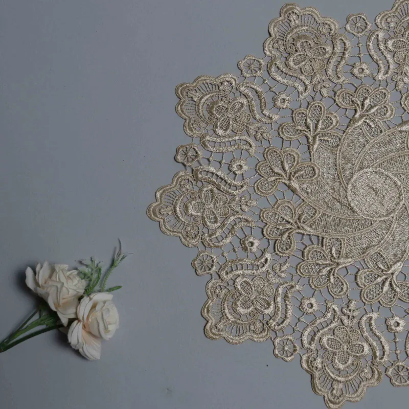 Eine beige Spitzendecke ragt von rechts ins Bild neben einem kleinen Strauß cremefarbener Rosen.