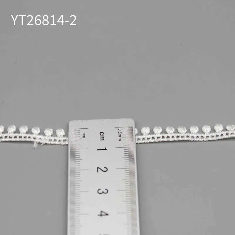 A ruler placed across the narrow white pompom trim labeled YT26814-2.