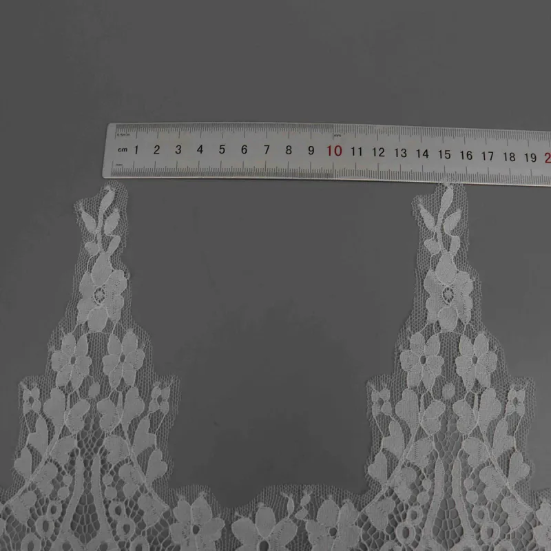 A horizontal ruler above two tall flower-tipped points of white lace.