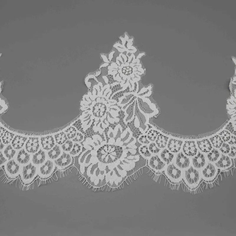 A single tall flower-and-leaf motif between curved openings in white lace.