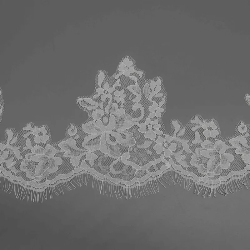 Close flat view of a tall leafy motif above the rounded lower border of white lace.