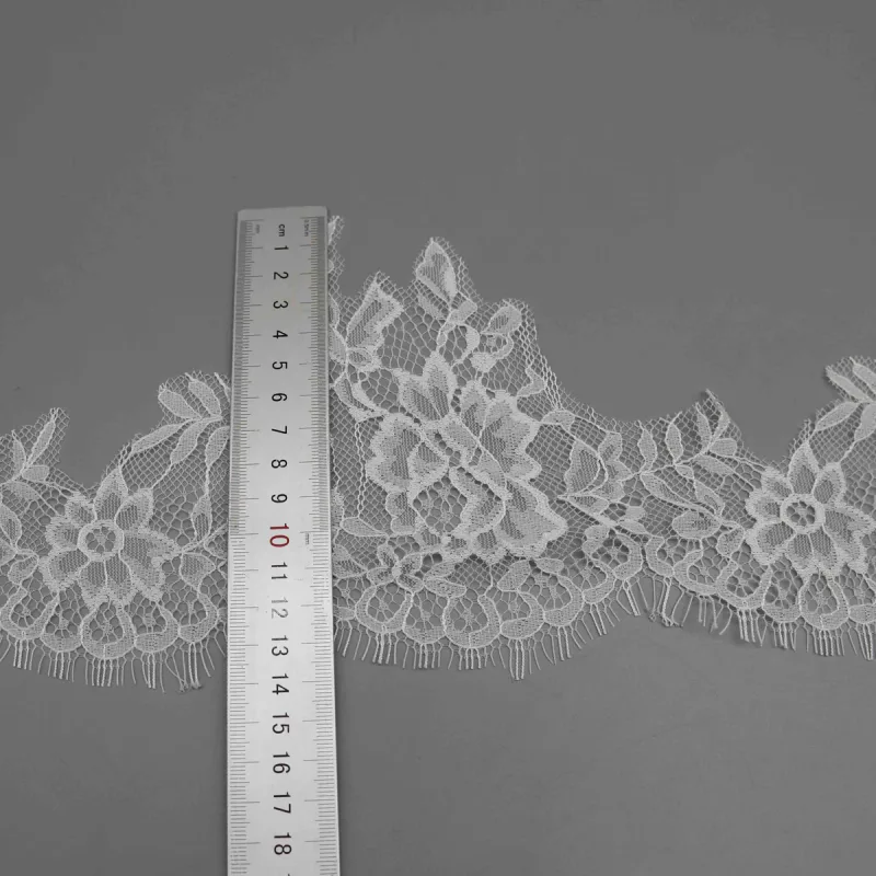 A vertical ruler across a leafy peak and the lower edge of white floral lace.