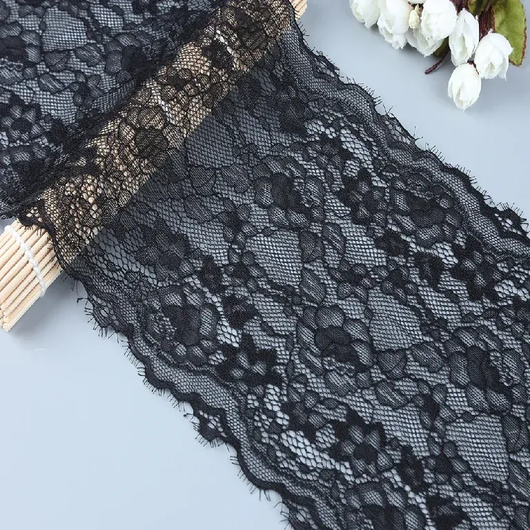 Galon de dentelle florale noire plié à côté de fleurs blanches.