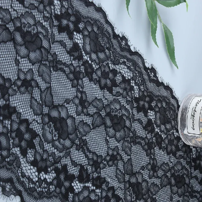 Vue rapprochée d’un galon de dentelle florale noire avec des volutes sur un fond en résille.