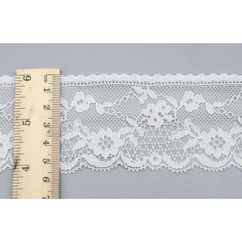 Une règle placée en travers d’un galon de dentelle florale blanche sur une surface grise. Une règle placée en travers d’un galon de dentelle florale blanche sur une surface grise.