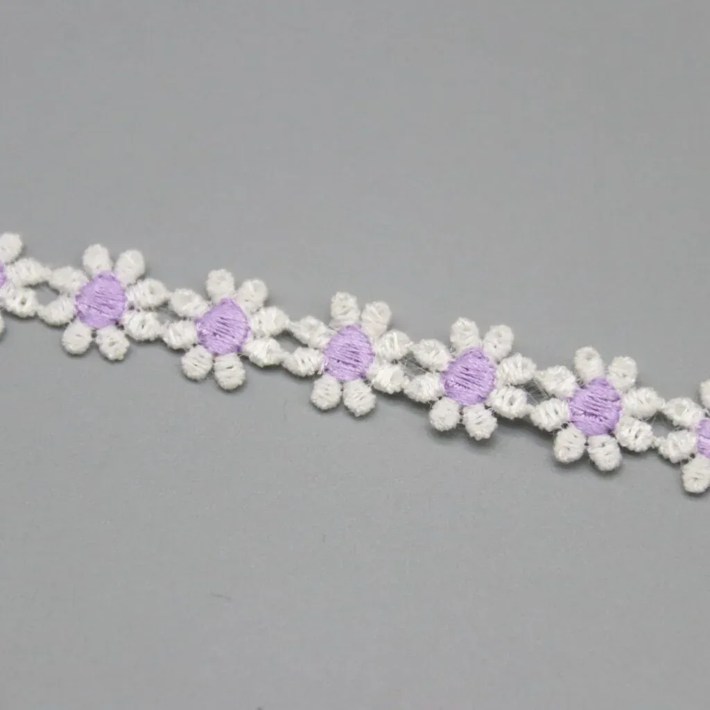 White daisy-chain trim with purple centers on a gray surface. White daisy-chain trim with purple centers on a gray surface.