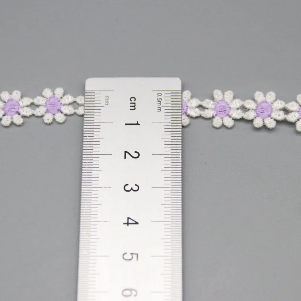 A ruler placed across white daisy-chain trim with purple centers. A ruler placed across white daisy-chain trim with purple centers.