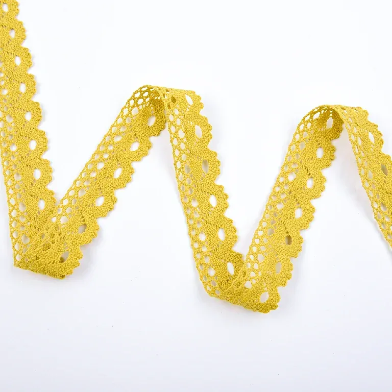 Galon de dentelle jaune à coquilles en éventail disposé en larges ondulations en zigzag sur une surface blanche.