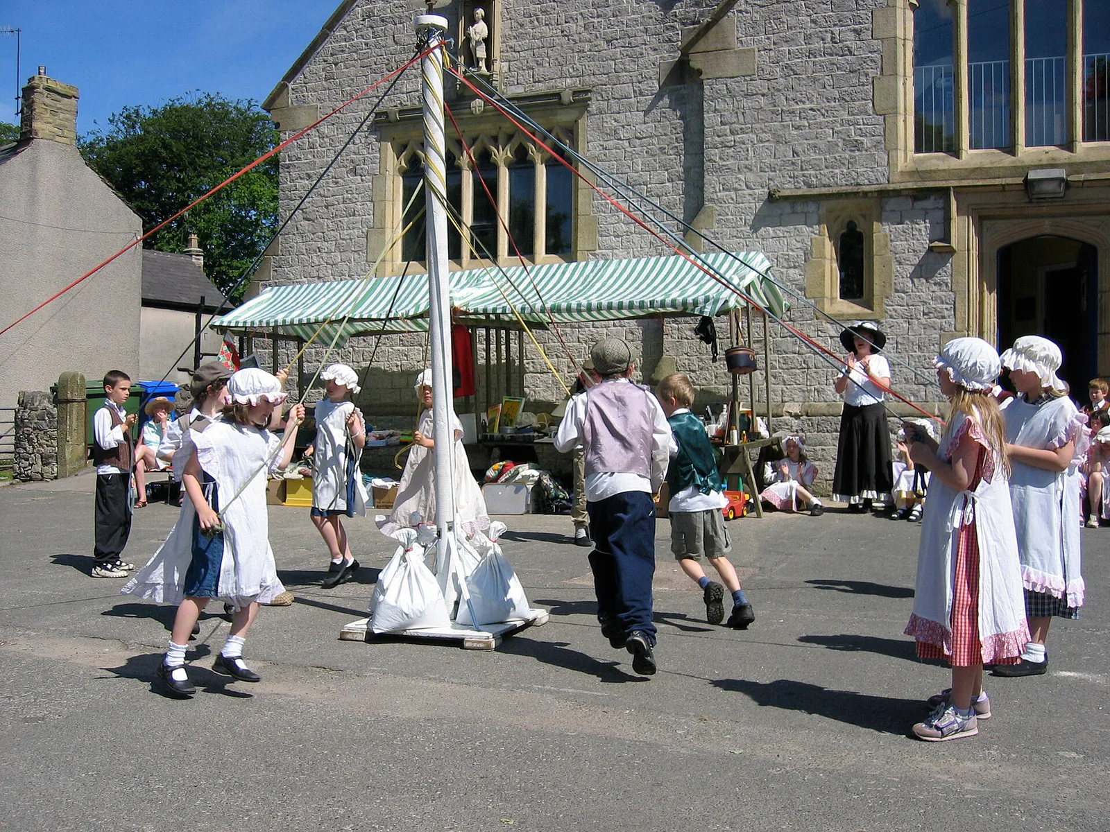 Las cintas del poste de mayo se extienden desde su parte superior hasta los bailarines de Litton Primary School, Inglaterra.