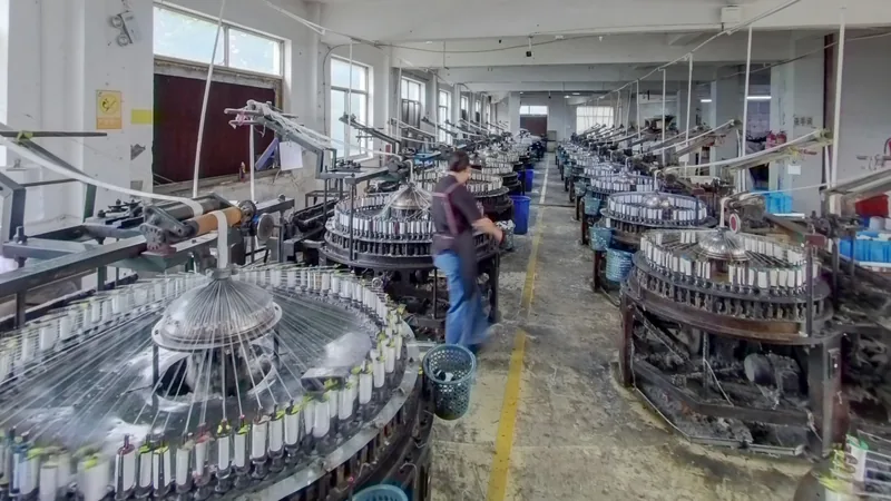 Rows of lace knitting machines and a worker on the YiTuo production floor.