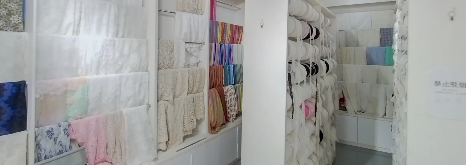 Lace samples displayed on wall panels and roll racks in YiTuo’s sample showroom.