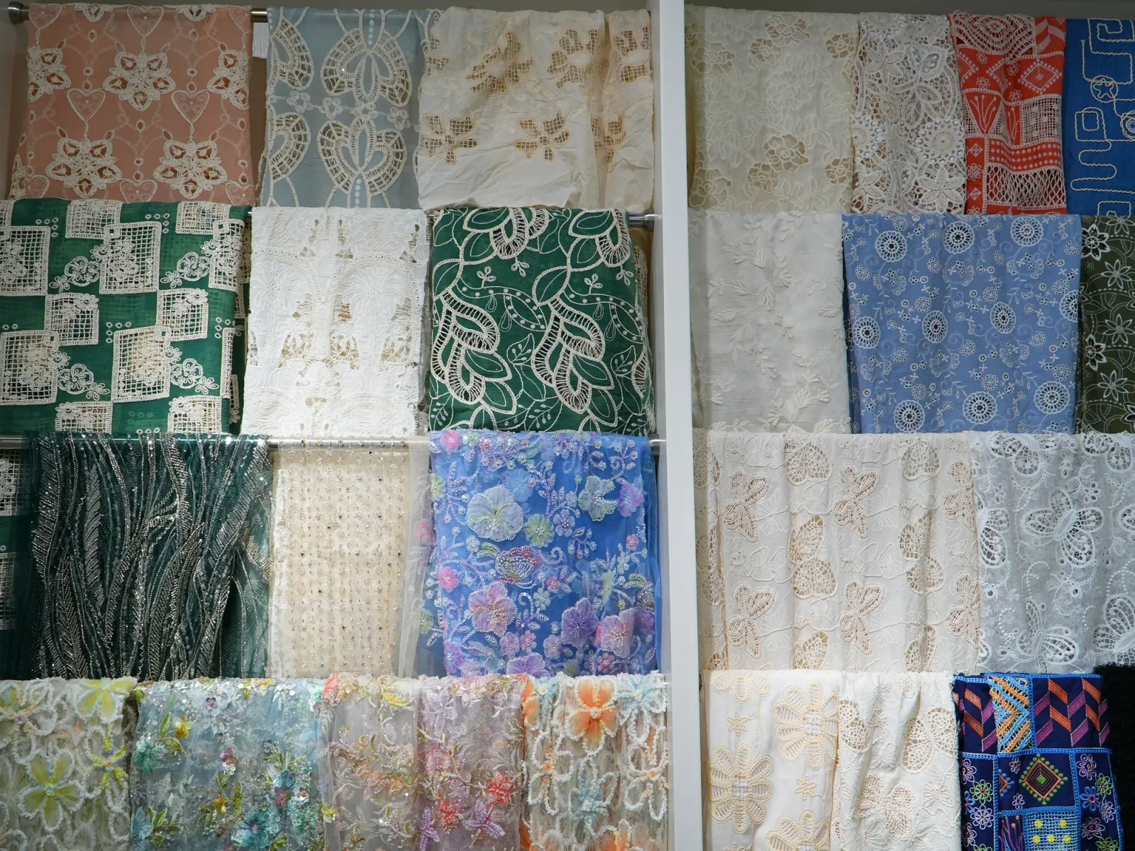 Panneaux d’échantillons brodés Panneaux d’échantillons de tissus brodés blancs et colorés disposés sur le mur d’une salle d’exposition