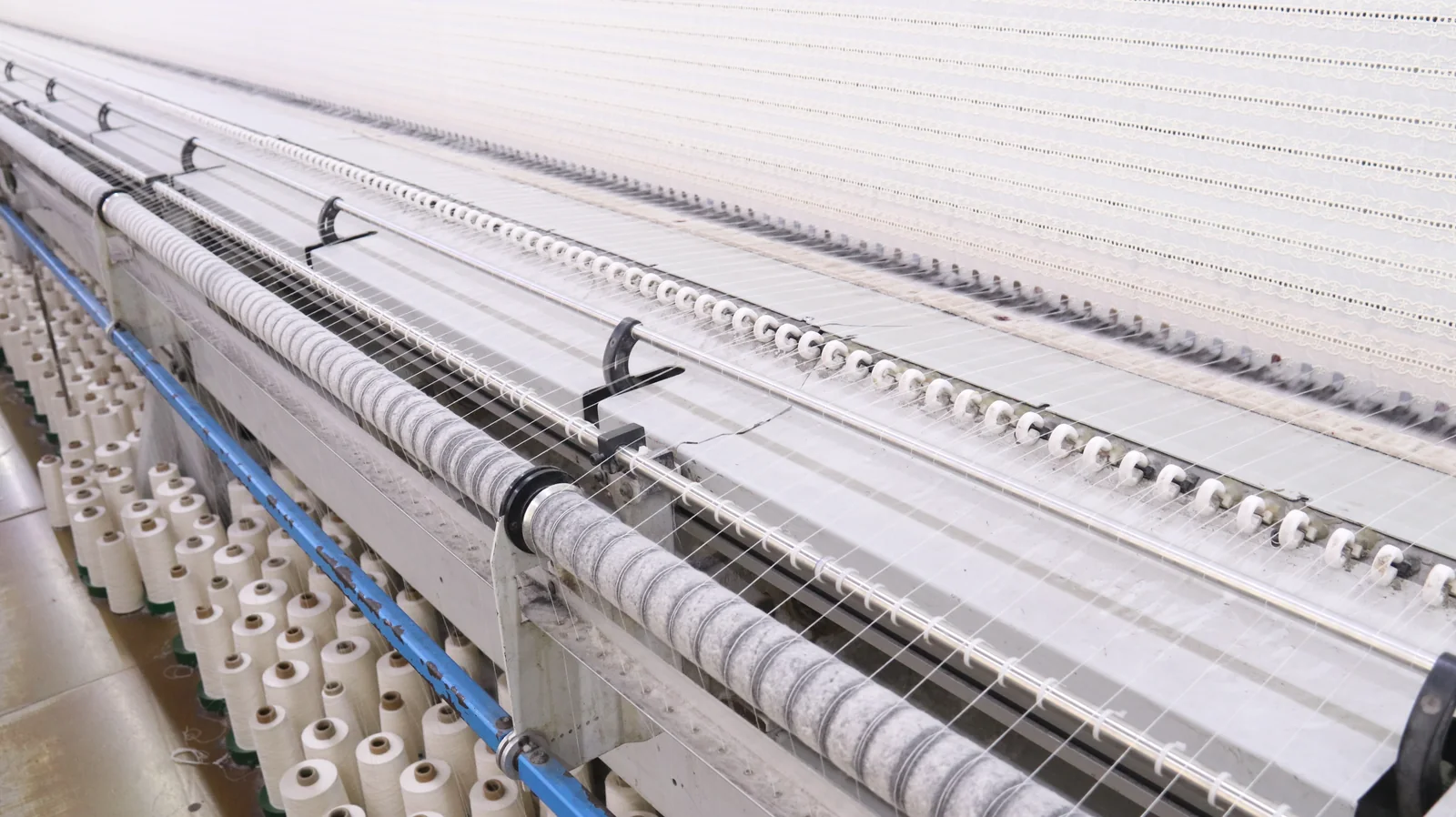 Détail d’une machine à broder Fils parallèles et guides-fils sur la zone de travail d’une machine à dentelle