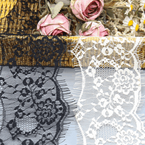 Close-up of factory-wholesale nylon eyelash lace trim in black and white, featuring intricate mesh embroidery with layered floral motifs for a 3D effect, and delicate, elongated eyelash fringe edges for added luxury; soft and breathable, ideal for high-end dress embellishments.