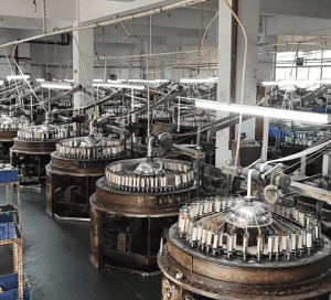 Overview of a large cotton thread lace production facility staffed by skilled workers and equipped with modern machinery.