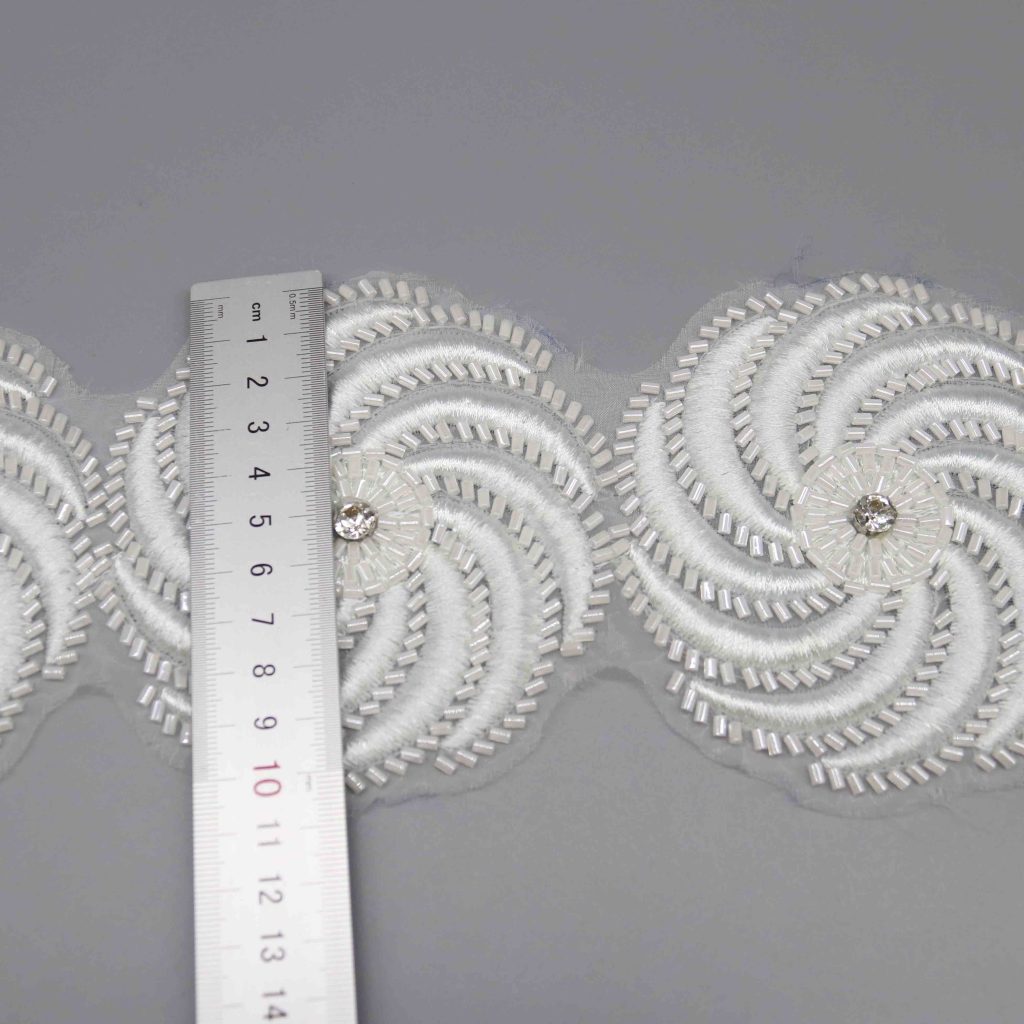 Precision‑cut embroidered lace motifs and neatly trimmed grosgrain ribbon edges illustrating reduced material waste and faster finishing.