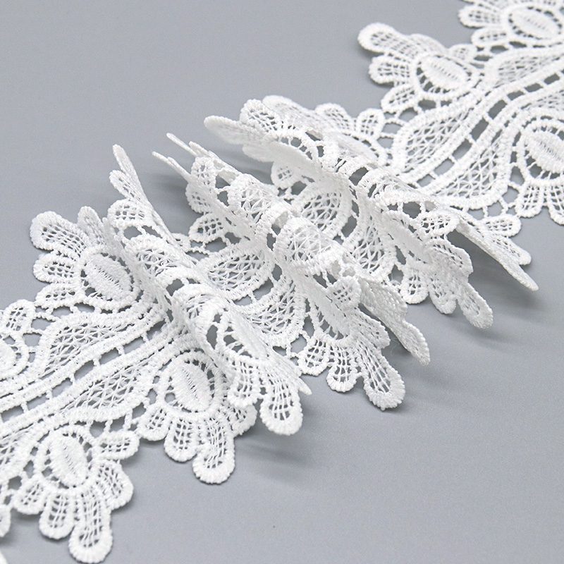 Macro view of sheer openwork water soluble lace next to a textured corded chemical lace border.