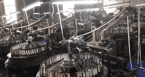Factory setting showing technicians operating embroidery equipment to produce custom pure cotton eyelet lace with reinforced borders for garments. 提问 解释 