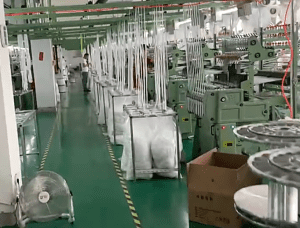 Interior view of a factory producing pure cotton embroidered eyelet lace trims, showing machines and rolls of durable border lace ready for bulk shipment.