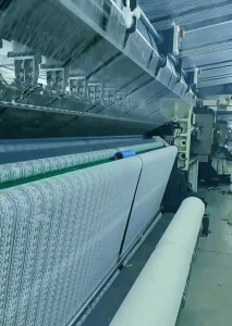 Interior view of a modern lace trim factory featuring high-tech embroidery machines producing intricate and high-quality lace fabrics in bulk.
