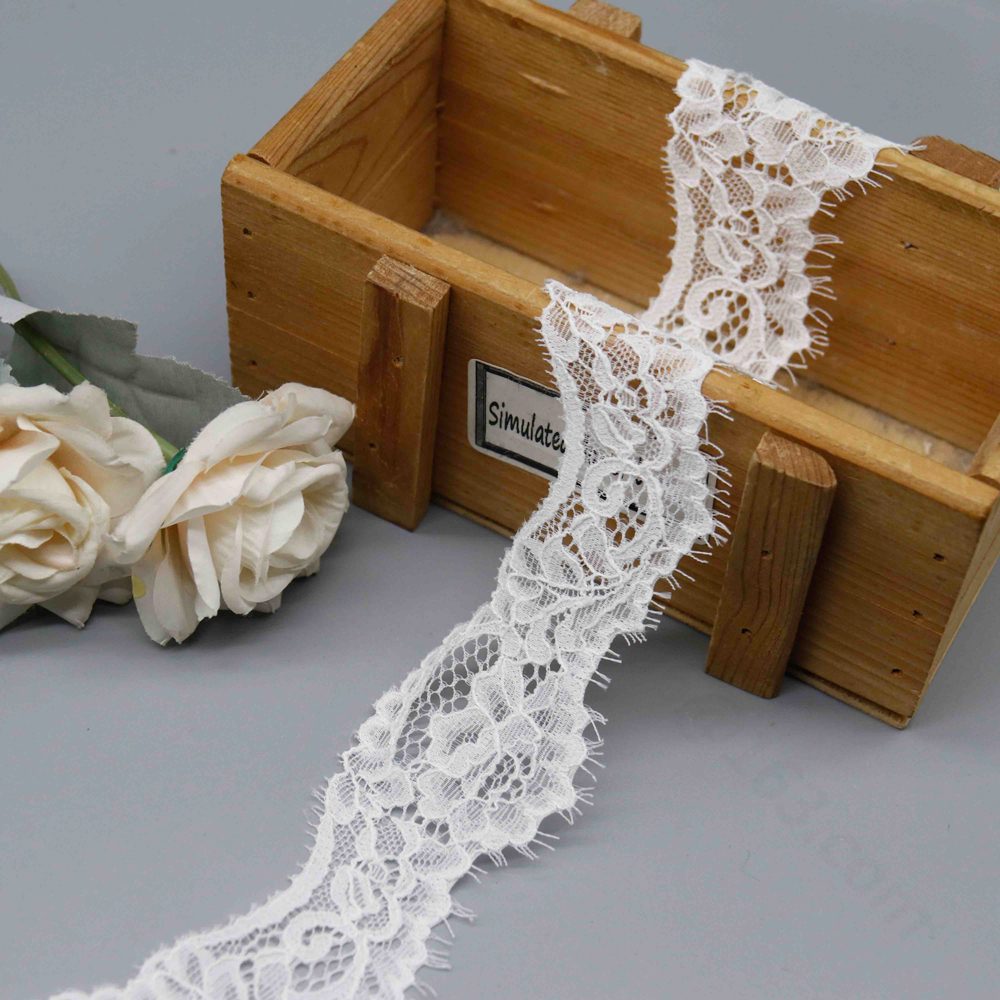Detailed view of ladies' French stretch eyelash lace trim in black and white, featuring refined floral vine embroidery on a transparent mesh base for depth and grace; elastic fabric with both-side scalloped waves and soft eyelash fringes enhances the romantic allure for neckline decoration and lingerie styling.
