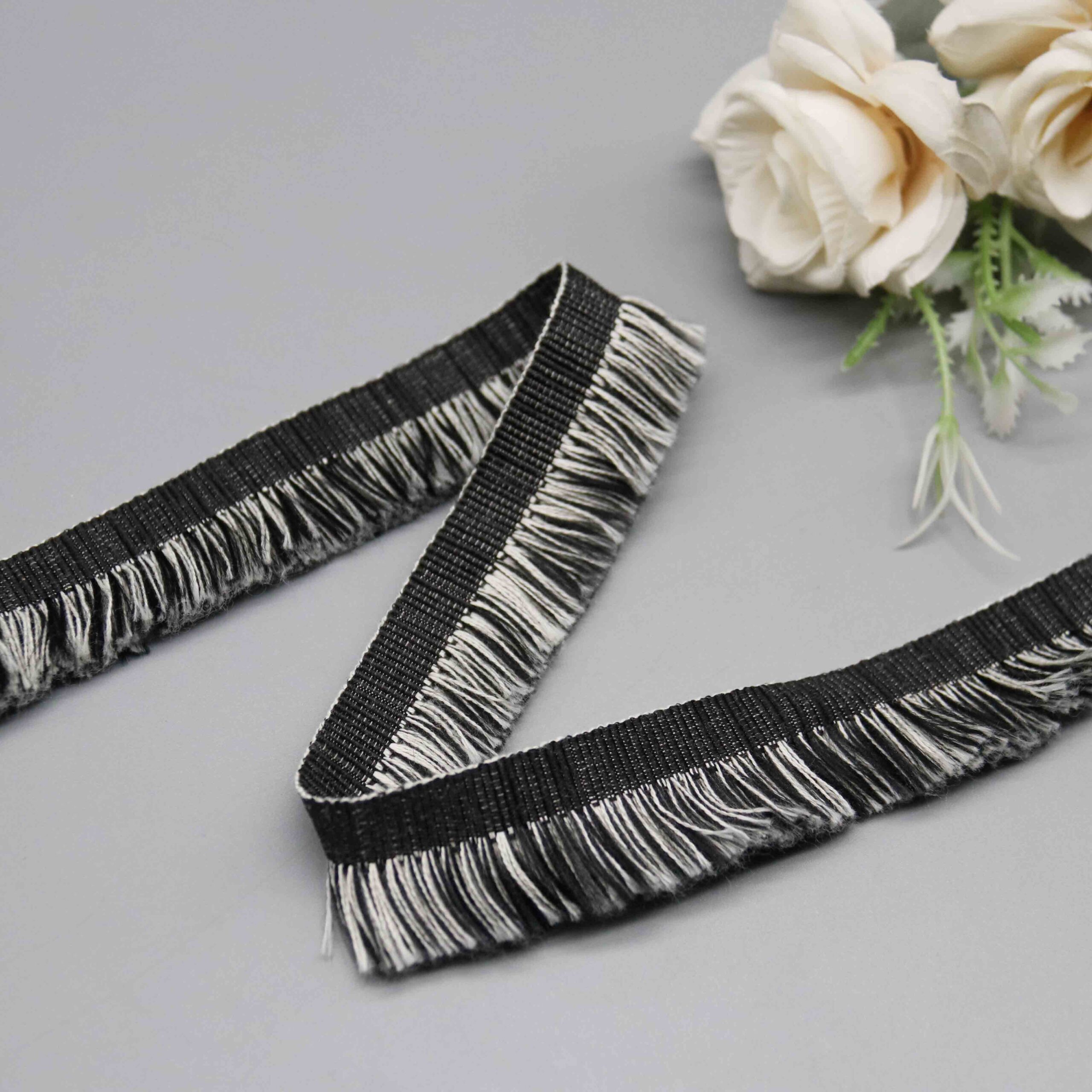 Angled shot capturing the silky polyester strand texture and uniform cut fringe ends.