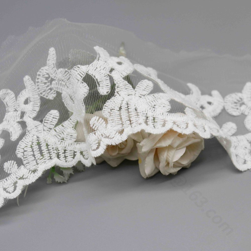 Macro close-up capturing curling vine motifs and dimensional satin-stitch thread craftsmanship.