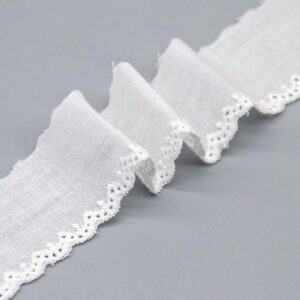 A close-up studio image of a 3cm wide, 100% cotton lace edging with a mini-scalloped border, shown next to a ruler for scale