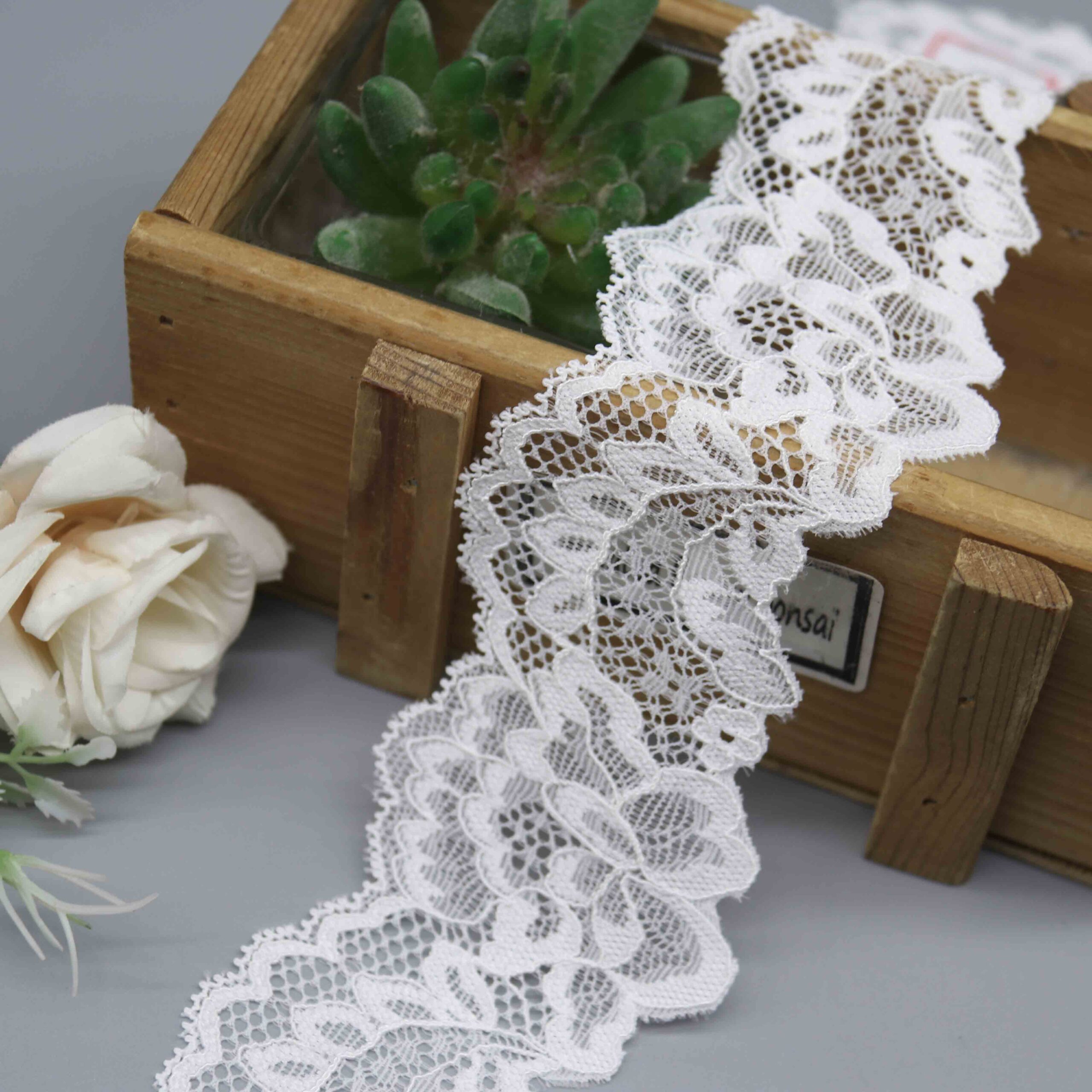 A studio photo of a 5.5cm wide elastic lace, model HDL-1155, showing its symmetrical scalloped edges and intricate floral pattern