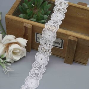 A studio photo of a 2.5cm wide white floral stretch lace trim, featuring a pattern of repeating floral medallions and scalloped edges.